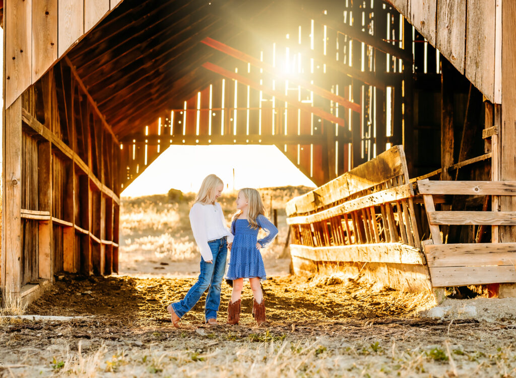 sibling photo in a barn at sunset 