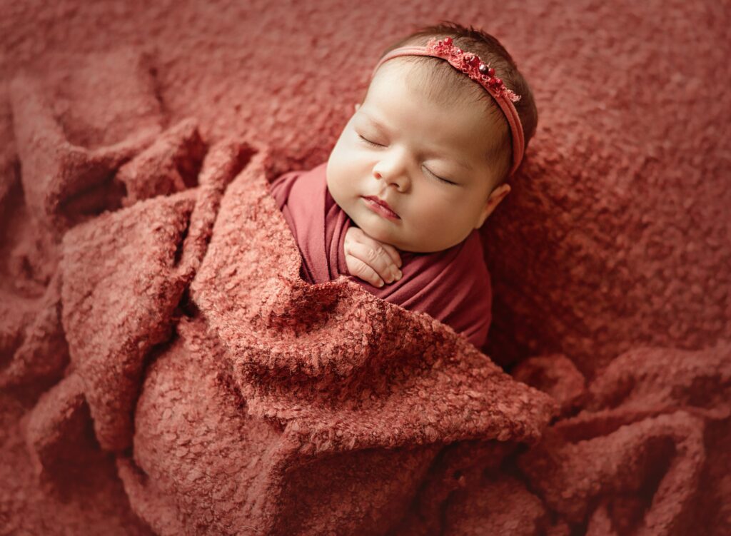 Baby wrapped in soft neutral blanket during safe newborn photo session in Yuba City studio