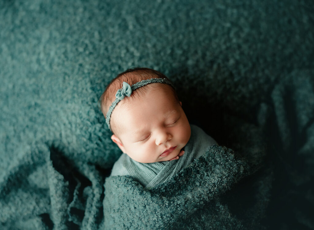 baby girl in teal colors on a fuzzy blanket